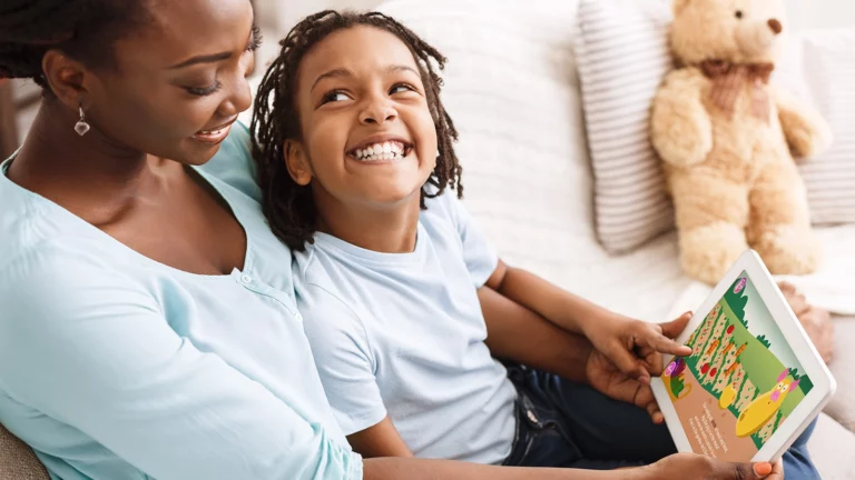 Mother and child happily using a tablet together while engaging with an educational app, Smart Tales, in a cozy home environment.